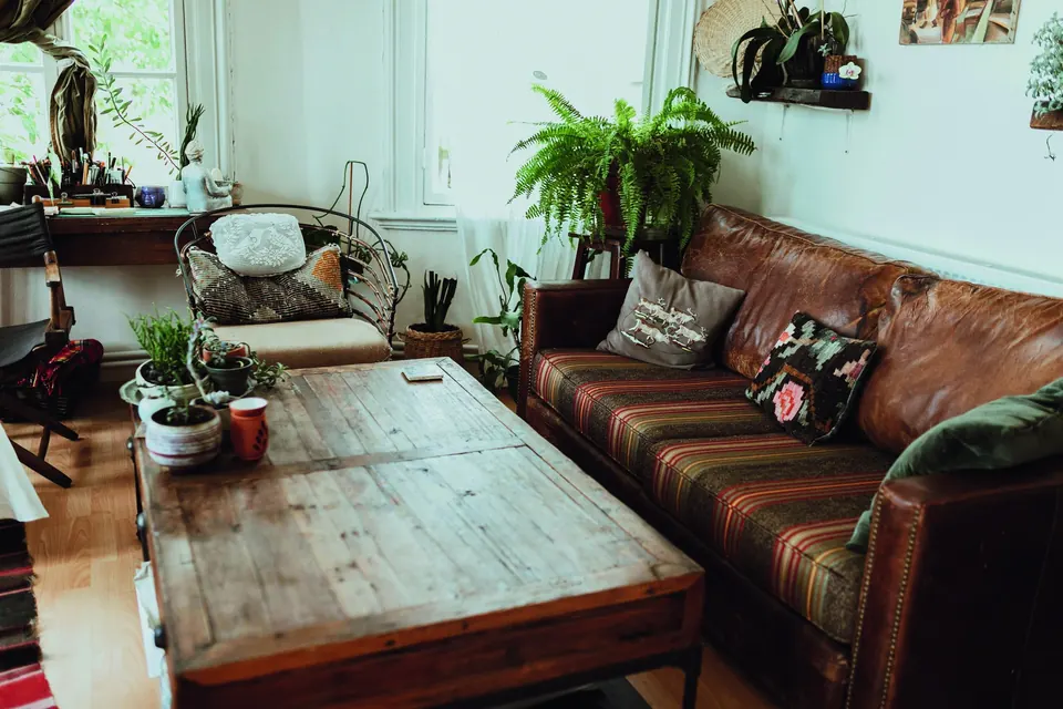 A boho living room with a leather sofa, a reclaimed-wood coffee table and lots of plants