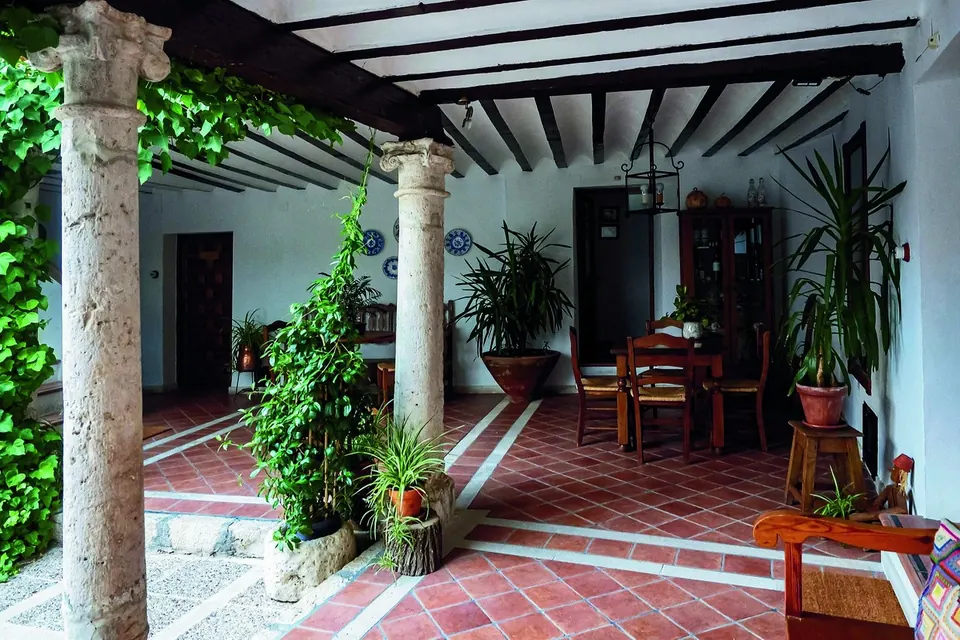 A Mediterranean courtyard with stone columns, terracotta floors and climbing greenery